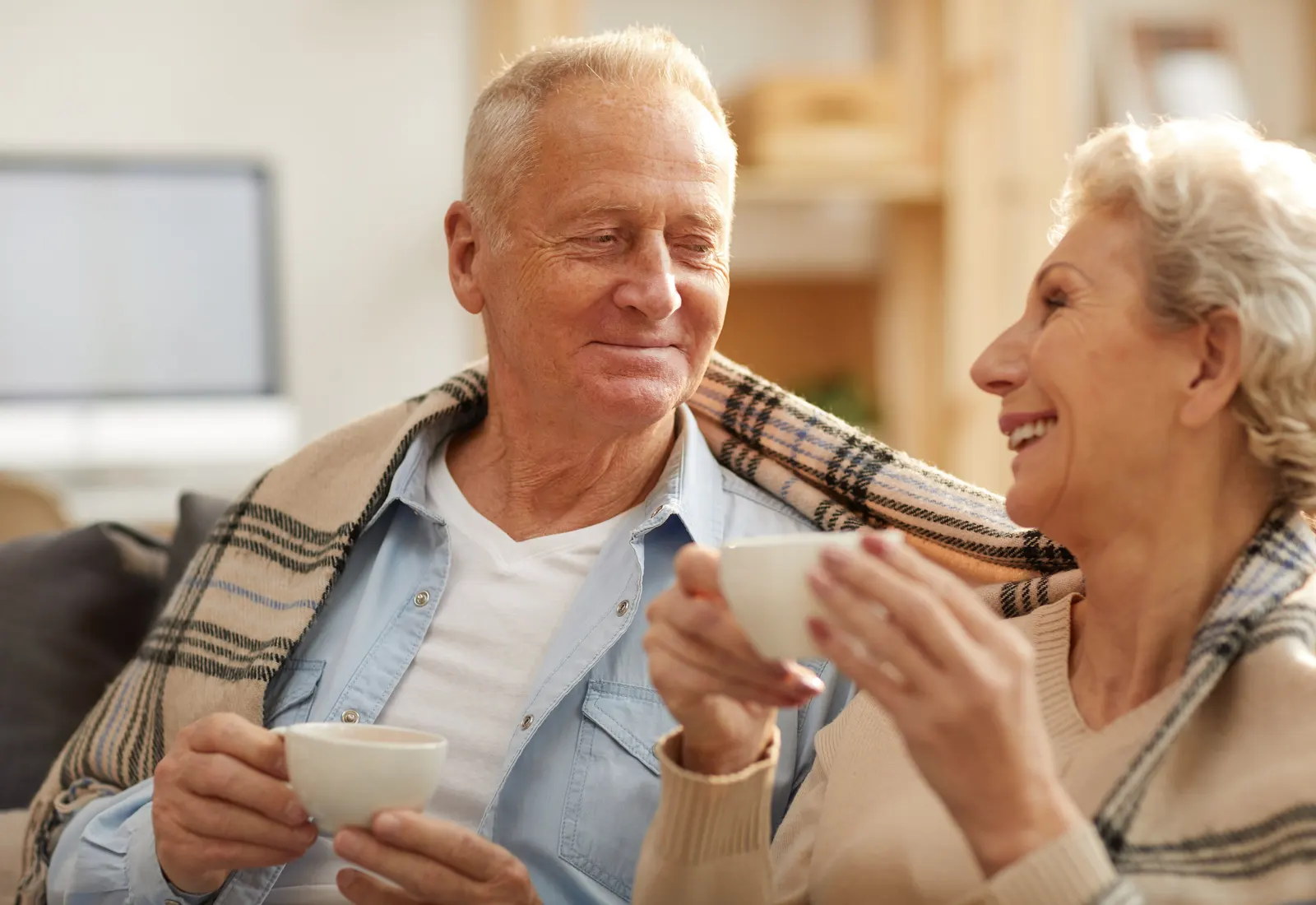 A senior couple sharing a cup of tea in a sunlit room
